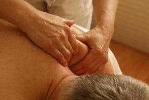 photo of man laying on his stomach having deep sports massage treatment on his shoulder