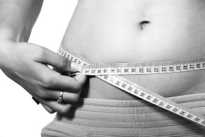 Image of female measuring a bare stomach with tape measure to check the effect of the weight loss service offered by David Marshall Personal Training based in Northampton